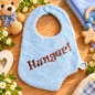 Preview: Hellblaues Baby-Lätzchen aus Frottee mit braun gesticktem Schriftzug Hunger und Druckknopf