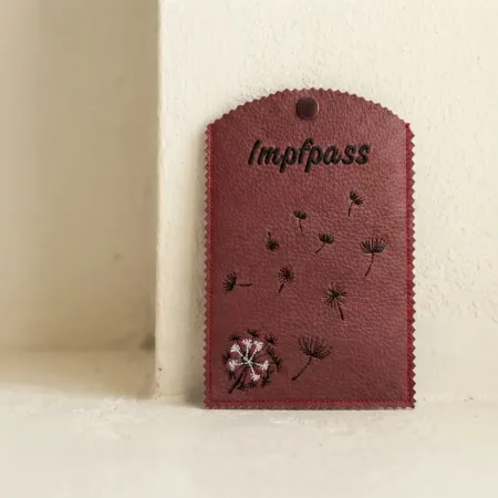 Dunkelrote Impfausweishülle mit Pusteblumen und Druckknopf