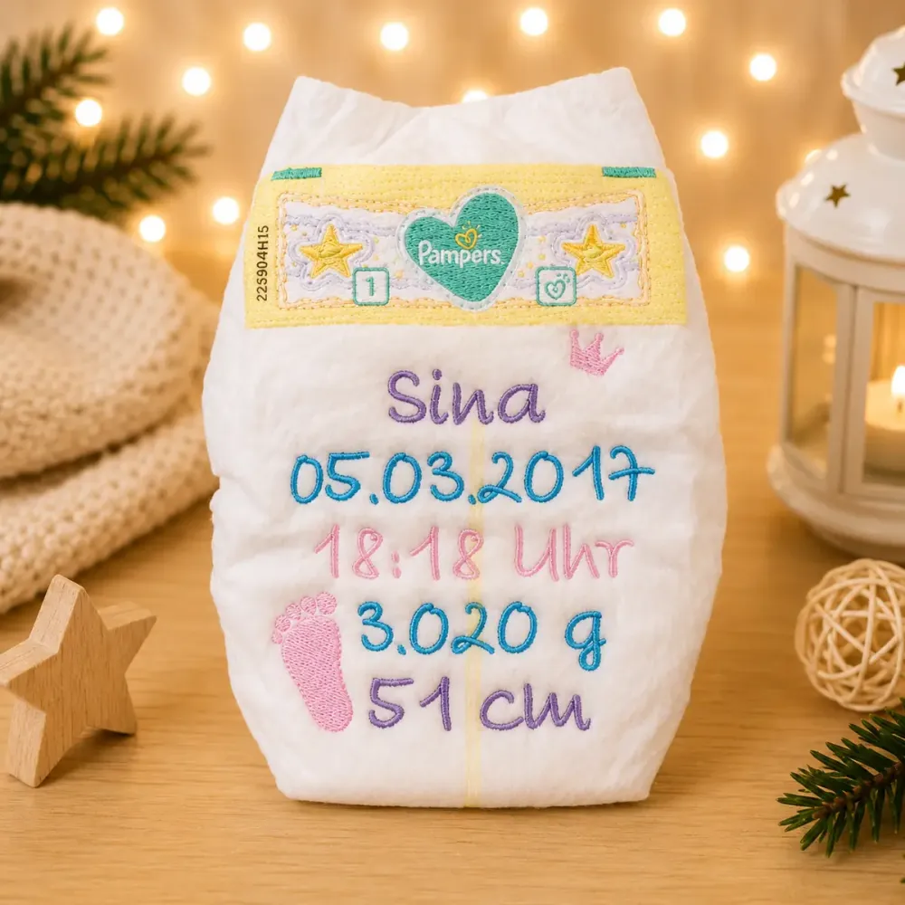 Personalisierte Babywindel bestickt mit Name, Geburtsdaten, einer Krone und kleinen Fußabdrücken.